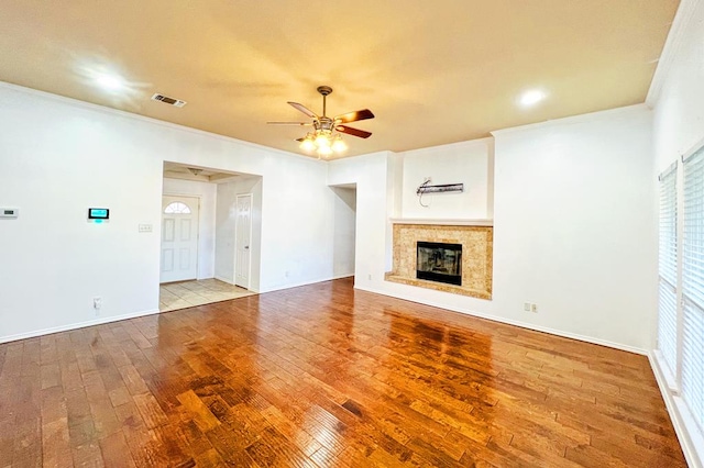 unfurnished living room featuring visible vents, crown molding, ceiling fan, hardwood / wood-style flooring, and a glass covered fireplace