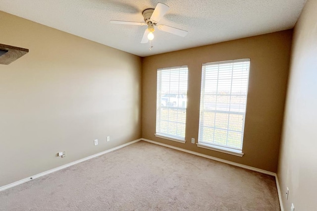 carpeted empty room featuring baseboards, a healthy amount of sunlight, a textured ceiling, and ceiling fan