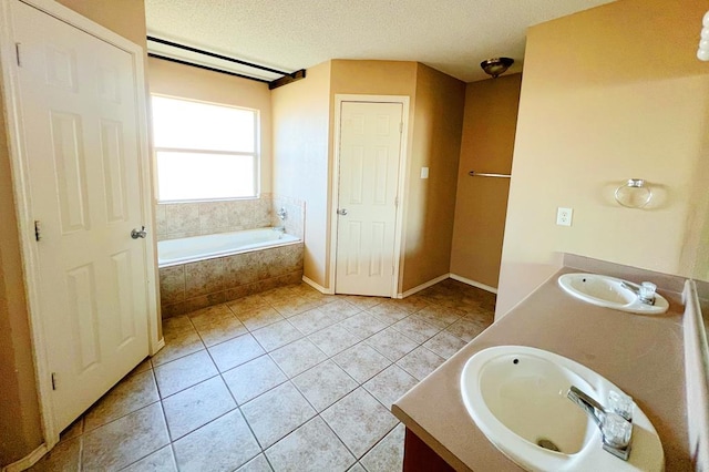 bathroom featuring a textured ceiling, a garden tub, double vanity, and a sink