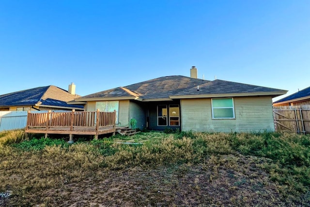 back of property with a deck, fence, and a chimney