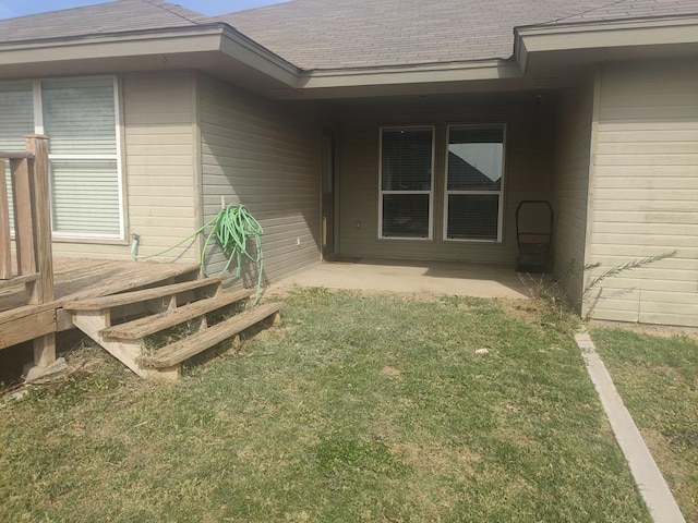 property entrance featuring a lawn and roof with shingles