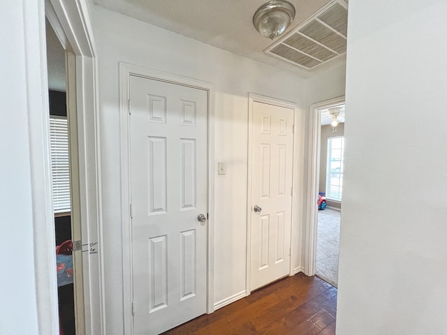 corridor featuring visible vents and dark wood-type flooring