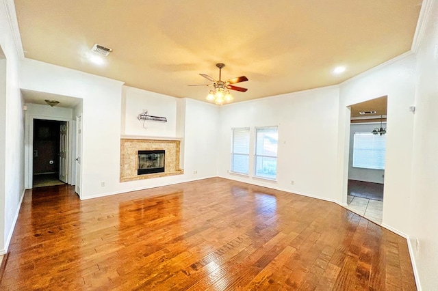 unfurnished living room with visible vents, ceiling fan, ornamental molding, wood finished floors, and a glass covered fireplace