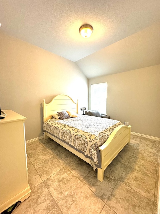 bedroom featuring lofted ceiling and a textured ceiling