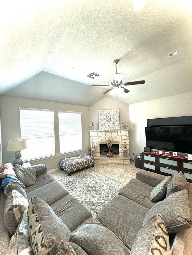 living room featuring lofted ceiling, ceiling fan, a fireplace, and a textured ceiling