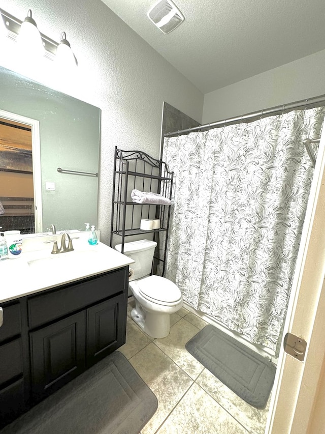 bathroom featuring vanity, tile patterned flooring, toilet, and a textured ceiling