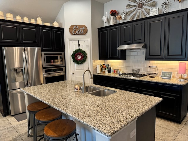 kitchen with an island with sink, appliances with stainless steel finishes, sink, and light tile patterned floors