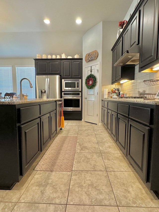 kitchen with stainless steel appliances, light tile patterned floors, and backsplash