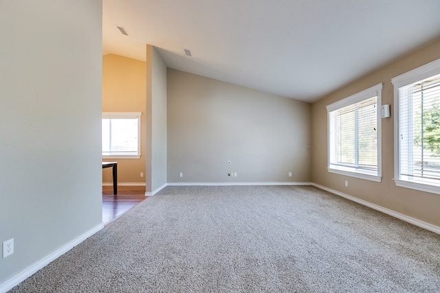 carpeted spare room featuring vaulted ceiling