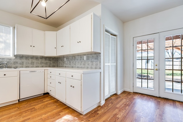 kitchen with backsplash, white dishwasher, light wood-type flooring, and white cabinets