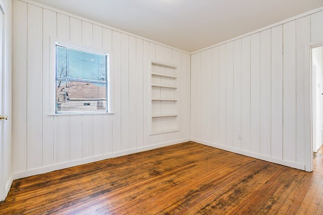 empty room with dark wood-type flooring and built in features