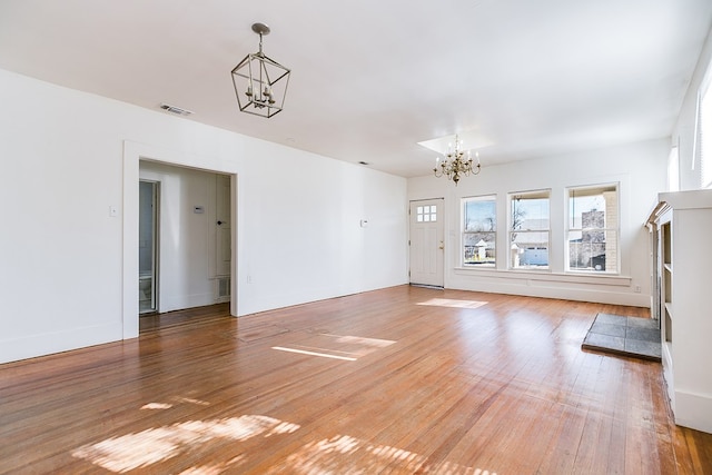 unfurnished living room featuring wood-type flooring and a notable chandelier