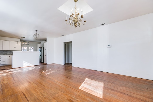 unfurnished living room featuring a chandelier and hardwood / wood-style floors