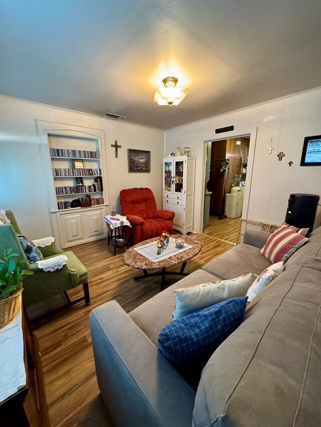 living room featuring wood-type flooring and built in features