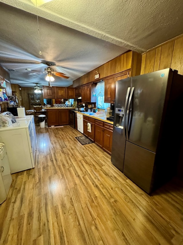 kitchen featuring washer and dryer, ceiling fan, stainless steel fridge with ice dispenser, a textured ceiling, and light hardwood / wood-style flooring