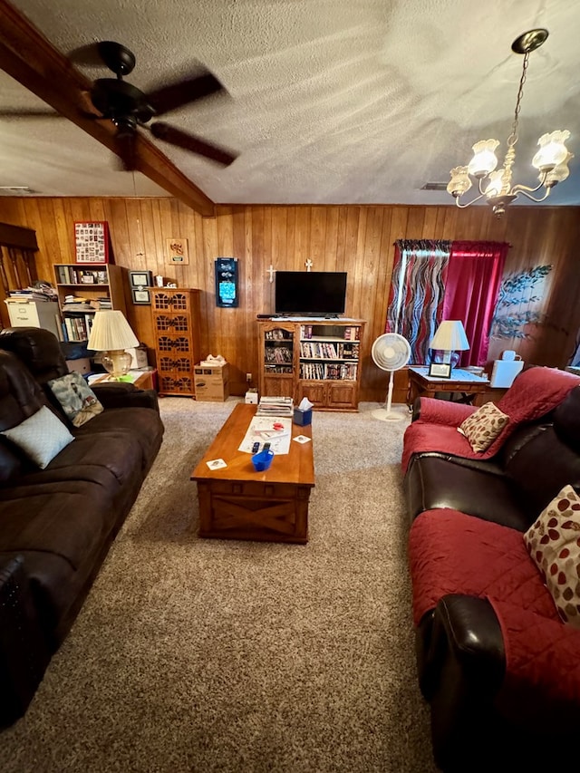 living room featuring beam ceiling, wooden walls, a textured ceiling, and carpet flooring