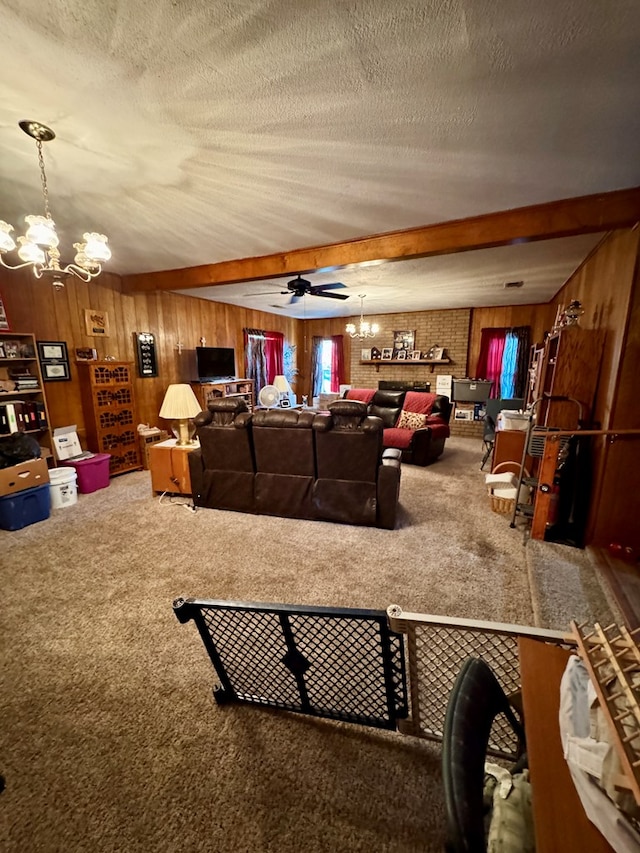 carpeted living room featuring beamed ceiling, wooden walls, ceiling fan with notable chandelier, and a textured ceiling