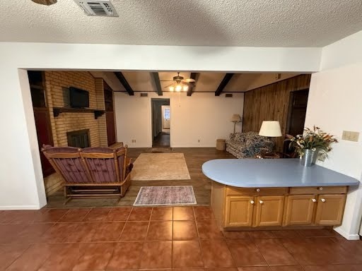 tiled living room featuring beam ceiling, ceiling fan, and a textured ceiling