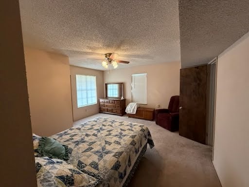 bedroom with a textured ceiling, carpet flooring, and ceiling fan