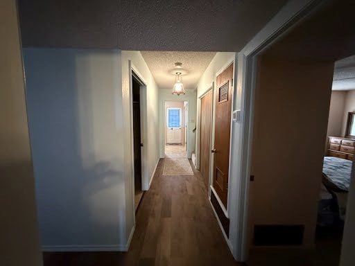 corridor featuring a textured ceiling and hardwood / wood-style floors