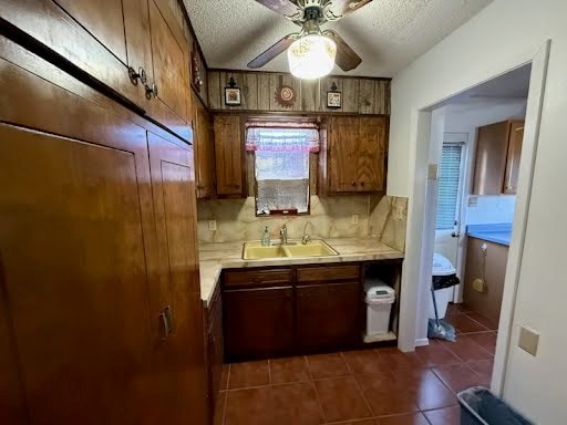 kitchen featuring dark tile patterned flooring, sink, a textured ceiling, and decorative backsplash