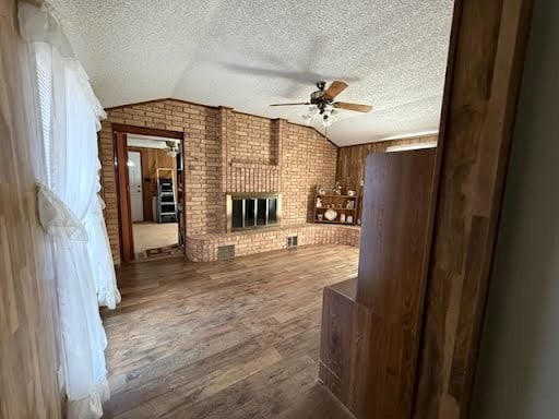 living room with a fireplace, vaulted ceiling, hardwood / wood-style flooring, and ceiling fan