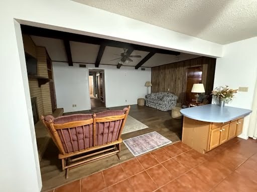 interior space featuring a textured ceiling, a fireplace, dark tile patterned flooring, and ceiling fan