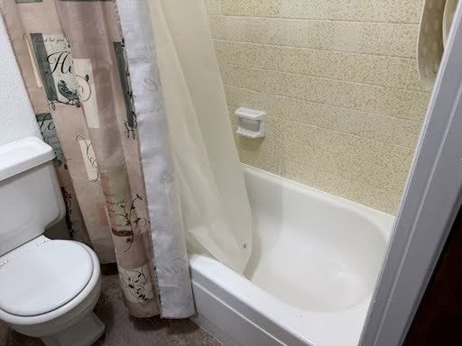 bathroom featuring shower / tub combo with curtain and toilet