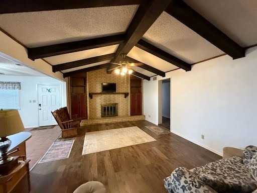 living room with a fireplace, vaulted ceiling with beams, ceiling fan, a textured ceiling, and dark wood-type flooring