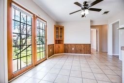 1246 E 20th St, San Angelo, TX 76903 - unfurnished room with wainscoting, a ceiling fan, light tile patterned flooring, and wooden walls