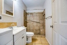 1246 E 20th St, San Angelo, TX 76903 - bathroom with vanity, tiled shower, and tile patterned flooring