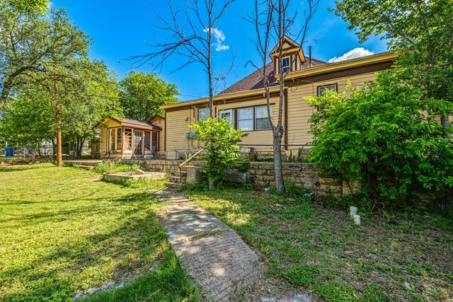 rear view of house with a sunroom and a lawn