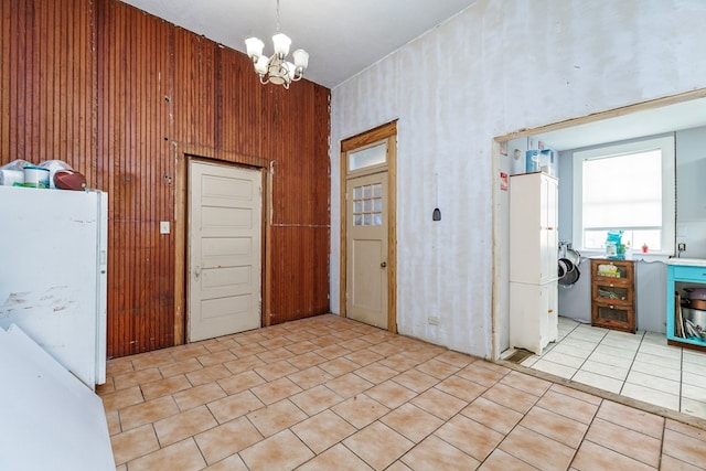 interior space featuring sink, light tile patterned floors, a notable chandelier, washer / dryer, and wood walls