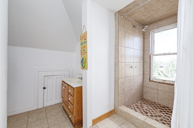 bathroom with tile patterned floors, vanity, lofted ceiling, and a tile shower