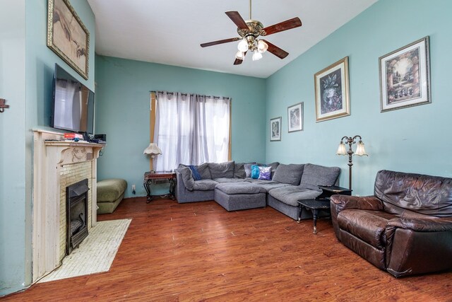 living room featuring ceiling fan, a fireplace, and wood-type flooring