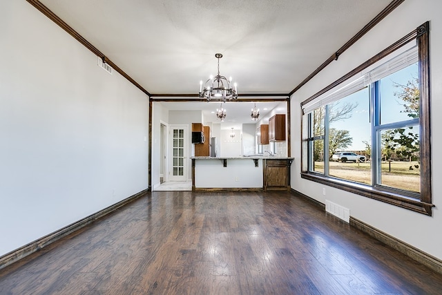 5438 S Loop 306, San Angelo, TX 76905 - unfurnished living room featuring visible vents, dark wood finished floors, an inviting chandelier, crown molding, and baseboards