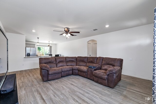 living room with ceiling fan with notable chandelier and light wood-type flooring