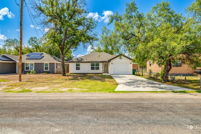 ranch-style home with a garage, a front lawn, and solar panels