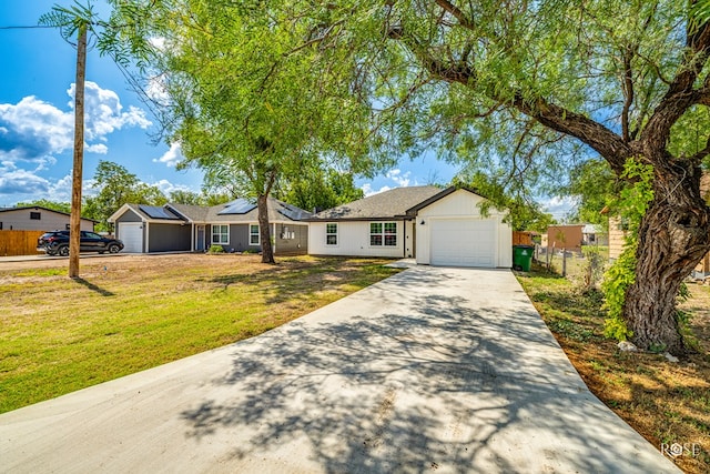 ranch-style home featuring a garage, a front lawn, and solar panels