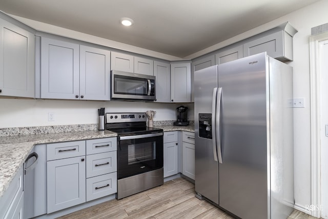 kitchen featuring appliances with stainless steel finishes, light stone countertops, and gray cabinetry