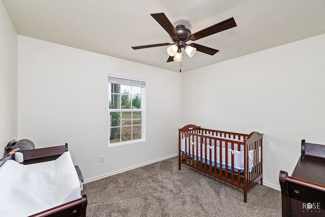 carpeted bedroom featuring a crib and ceiling fan