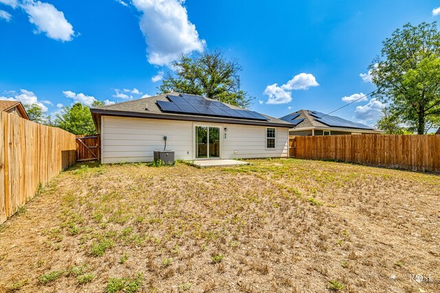 rear view of property with cooling unit, a yard, a patio, and solar panels