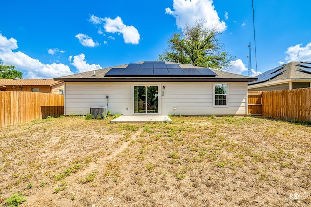 back of house with solar panels, central AC, a lawn, and a patio area