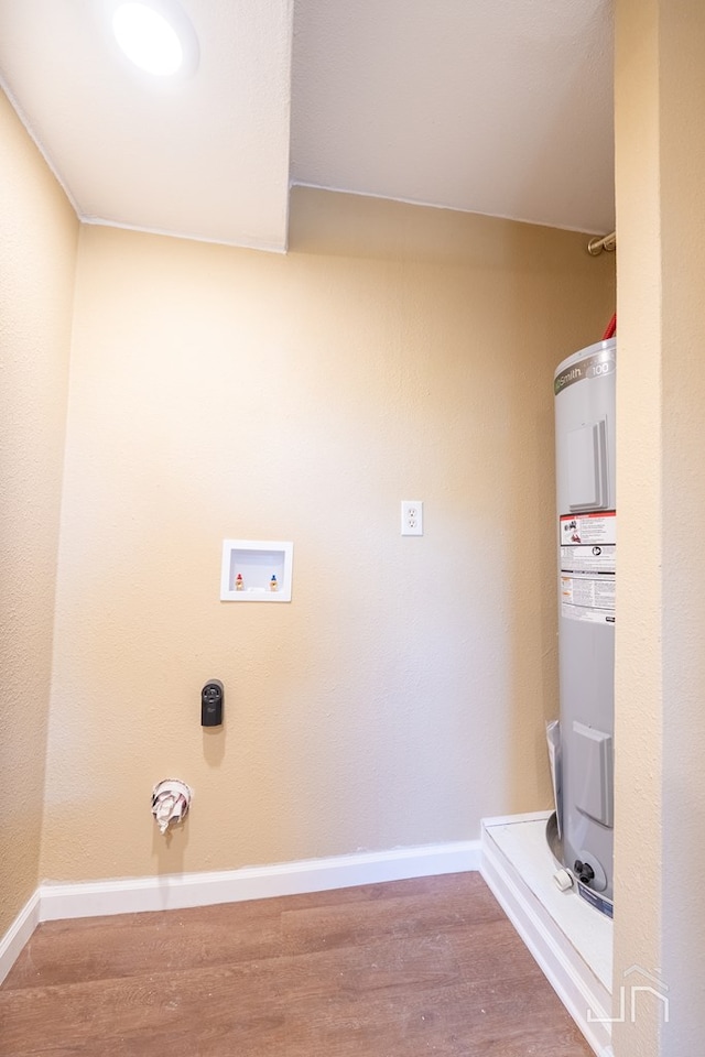 1317 18th St, San Angelo, TX 76903 - washroom featuring water heater, wood finished floors, washer hookup, and baseboards