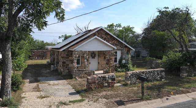 1317 18th St, San Angelo, TX 76903 - bungalow with stone siding, solar panels, covered porch, and driveway