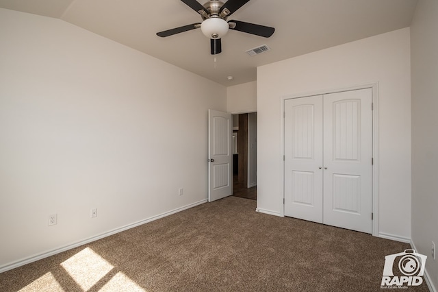 unfurnished bedroom featuring baseboards, visible vents, vaulted ceiling, dark carpet, and a closet