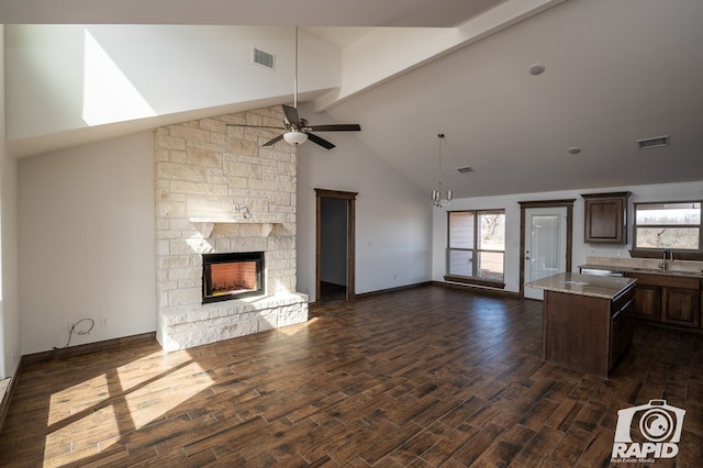 unfurnished living room featuring ceiling fan, a stone fireplace, dark wood finished floors, and visible vents