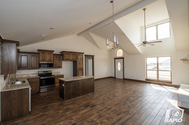 kitchen featuring dark wood-style floors, appliances with stainless steel finishes, open floor plan, a sink, and beam ceiling