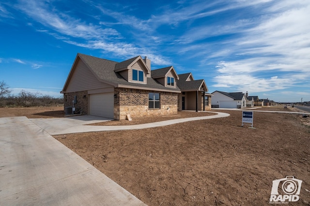 view of front of house with brick siding, a chimney, concrete driveway, central AC, and a garage