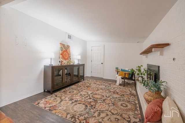 sitting room featuring visible vents, baseboards, a brick fireplace, and wood finished floors